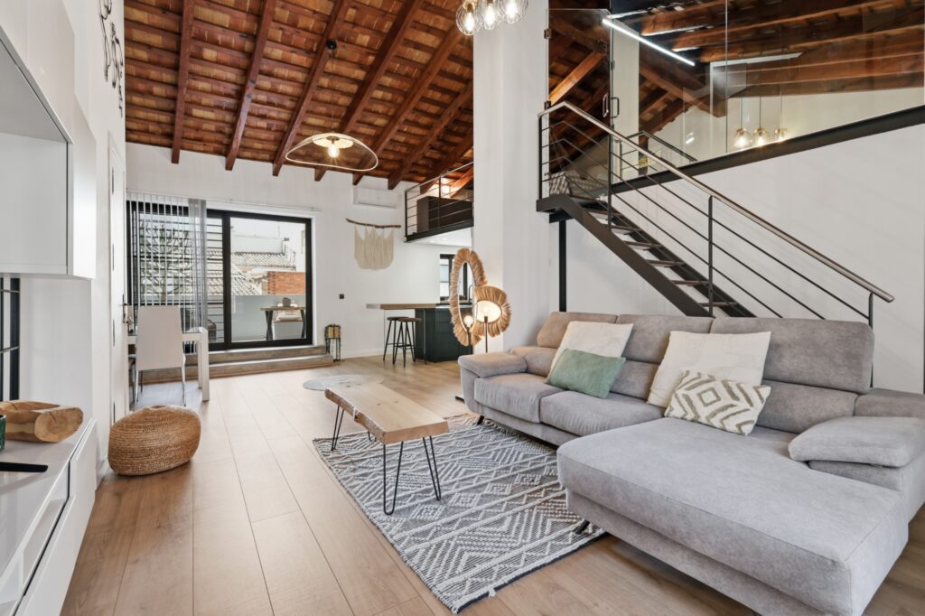 Interior de una vivienda con techo de madera, luz natural y escalera, fotografiado por Fotaria