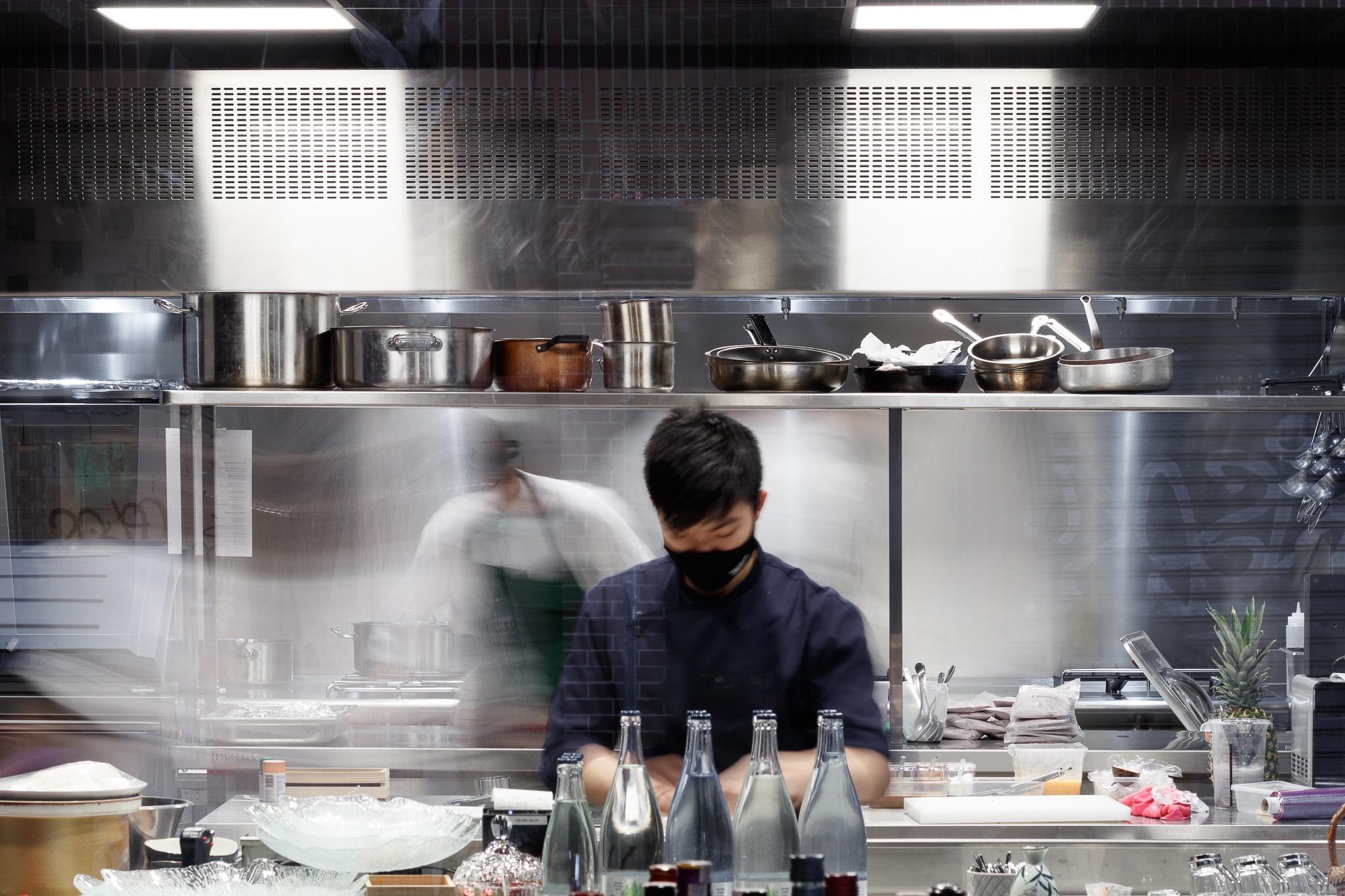 Cocina abierta de un restaurante en funcionamiento, con cocineros y zona de preparación