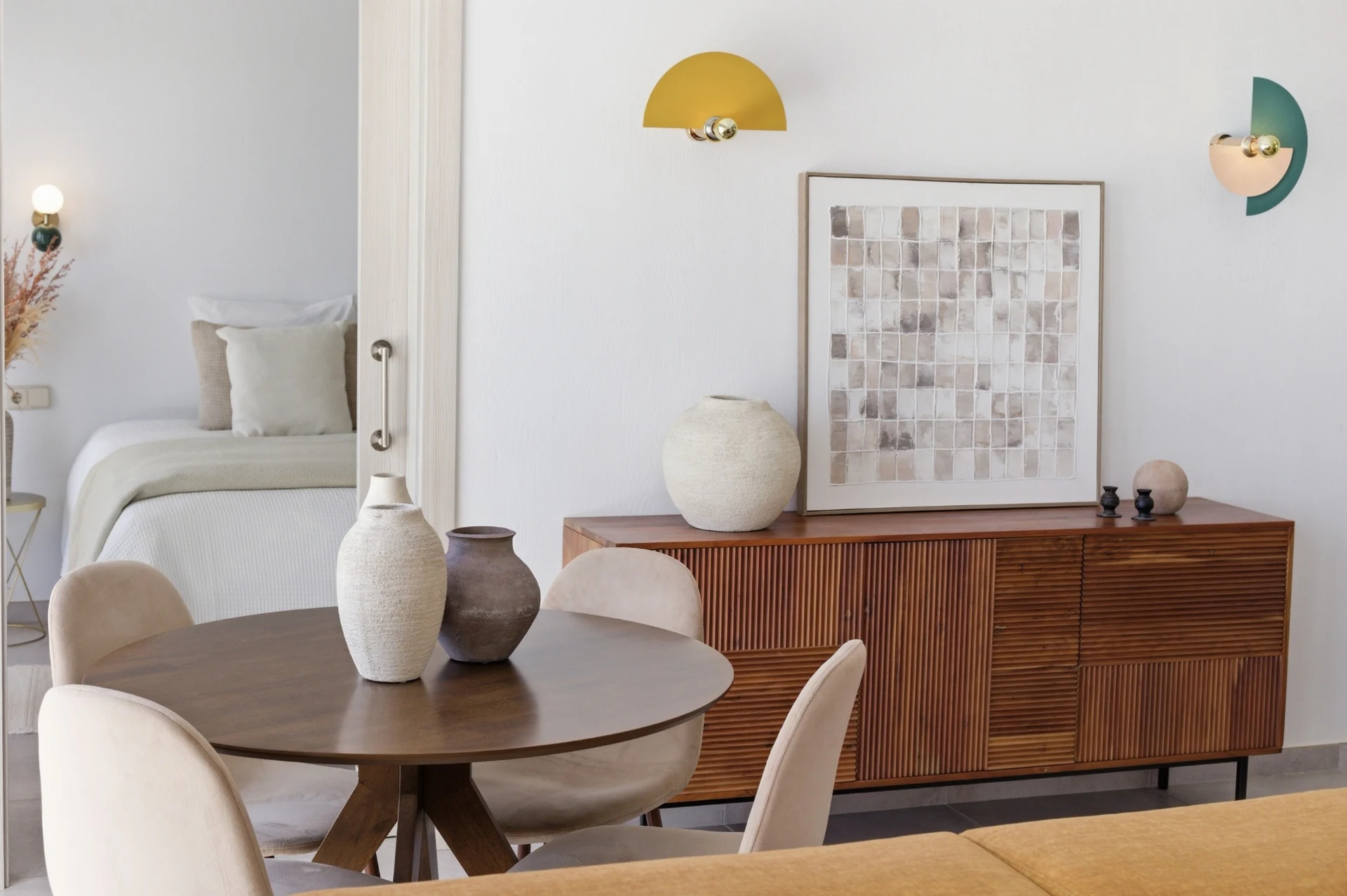 Comedor con mesa redonda, aparador de madera y acceso al dormitorio