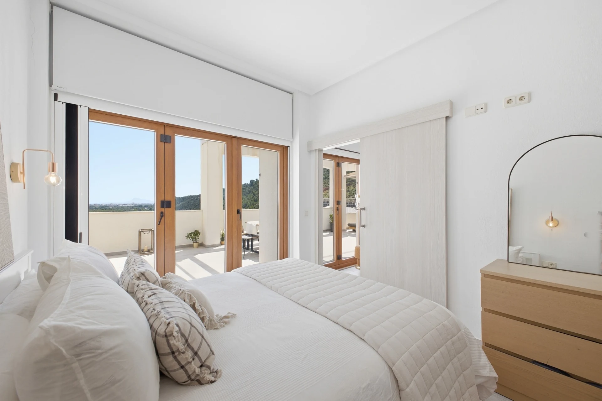 Dormitorio con cama y puertas acristaladas hacia la terraza