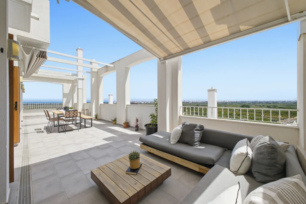 Terraza con pérgola, sofá y comedor exterior