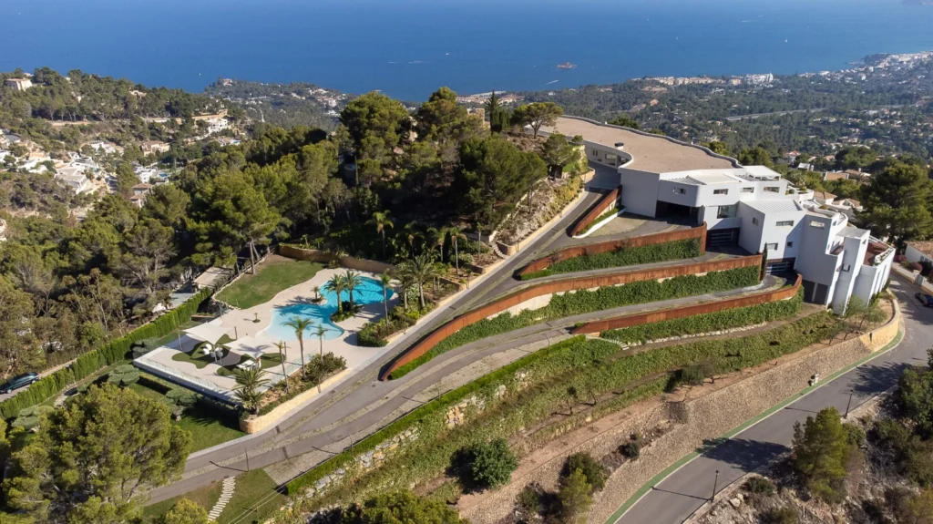 Vista aérea de un edificio residencial, piscina y entorno con el mar al fondo